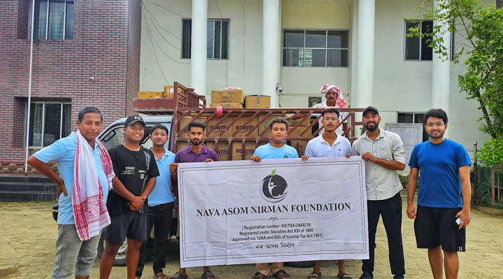 NANF volunteers with a banner beside a truck loaded with relief supply cartons in Teok, Jorhat, Assam